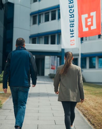 Mitarbeitende laufen zum Eingang der HEBERGER Gruppe Mitarbeitende laufen zum Eingang der HEBERGER Gruppe